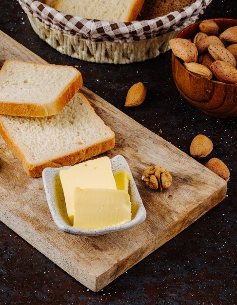 Side view butter with white bread almond and walnut on a board