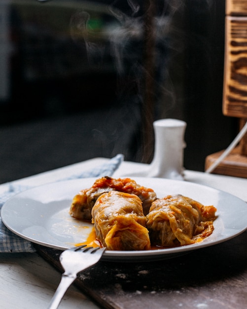 Вид сбоку голубцы с мясом рисом и овощами на тарелке