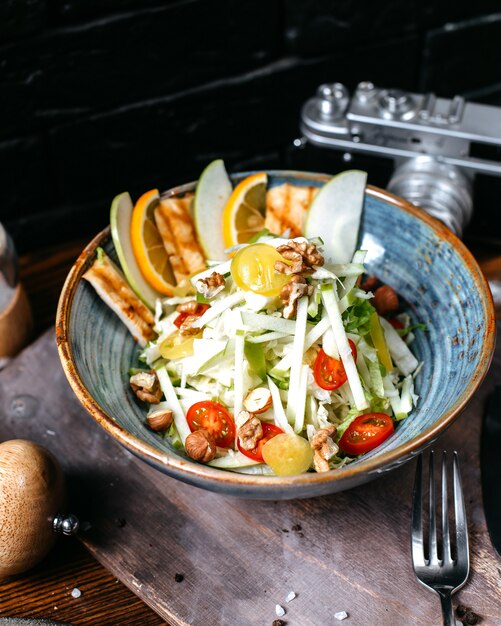 Side view of caesar salad with chicken and parmesan cheese in a bowl on dark