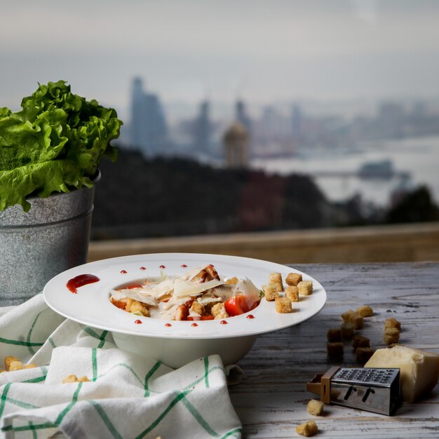 Side view caesar salad with crackers and cheese and lettuce in white plate