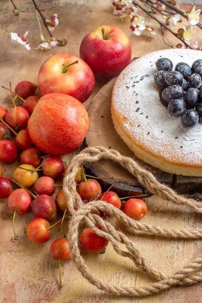 Side view a cake an appetizing cake with grapes apples berries rope tree branches