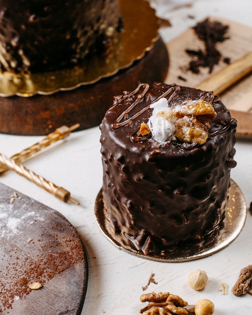 Side view of cake covered with chocolate and walnuts on the table