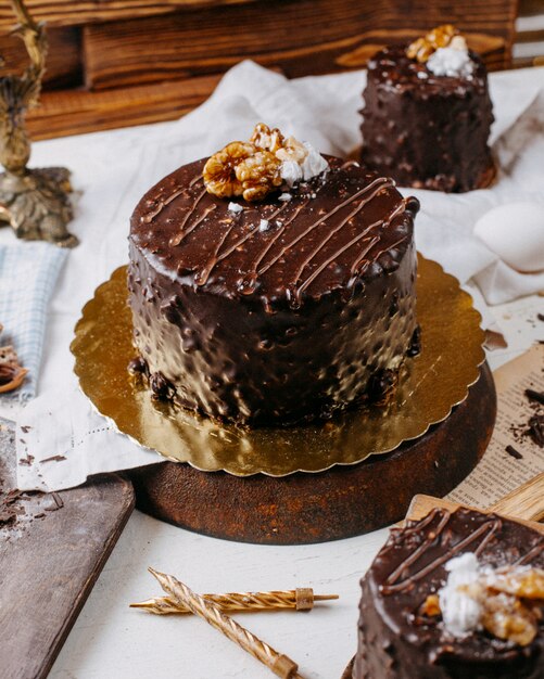 Side view of cake covered with chocolate and walnuts on the table