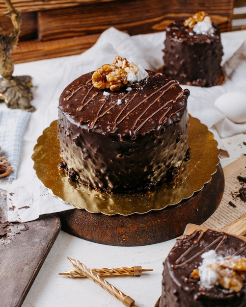 Вид сбоку торт покрытый шоколадом и грецкими орехами на столе