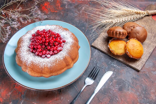 Side view cake cupcakes four cupcakes a cake with red currants knife fork wheat ears