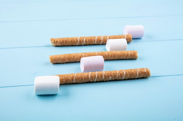 Side view of candies and crispy sticks on blue background