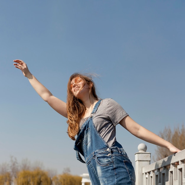 Side view of of carefree woman posing with arm up