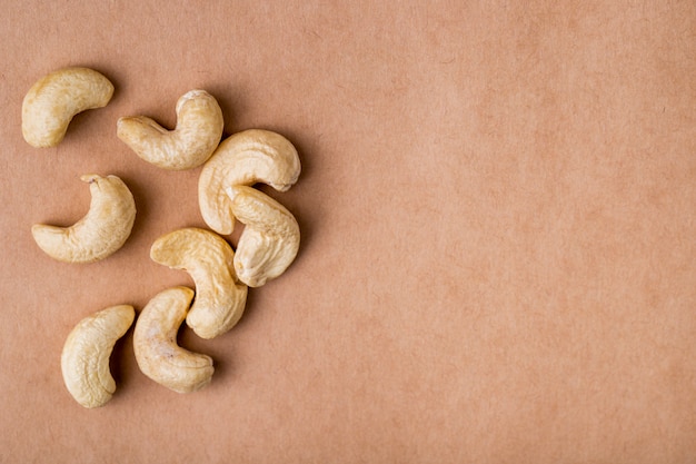 Free photo side view of cashews on old paper texture background with copy space