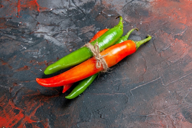 Free photo side view of cayenne peppers in different colors and sizes tied in one another with rope on mixed color table