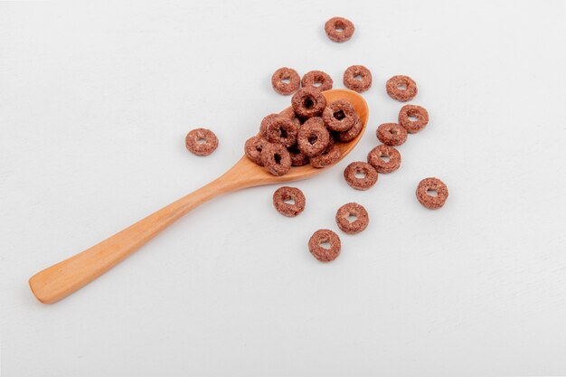 Side view of cereals in wooden spoon on white surface