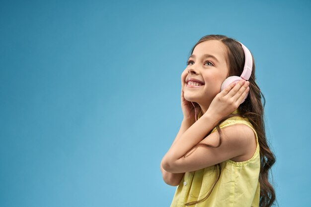 Side view of cheerful girl in headphones listening music