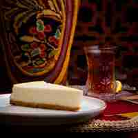 Foto gratuita torta di formaggio di vista laterale con bicchiere di tè in piatto bianco