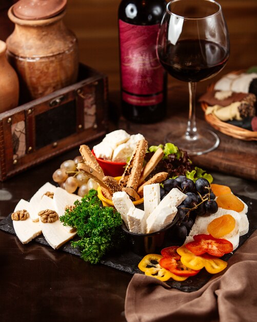 Side view cheese plate with grapes and a glass of red wine