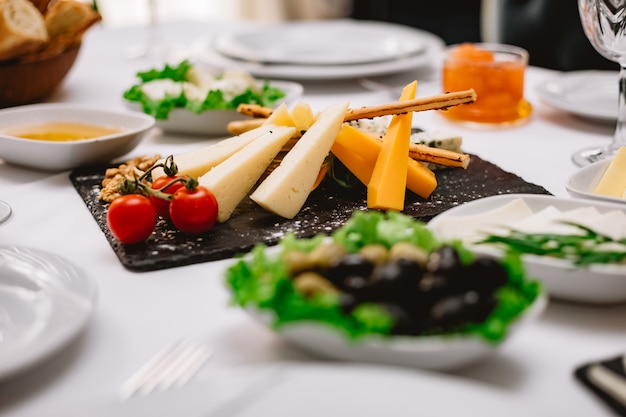 Free photo side view cheese plate with tomatoes and nuts