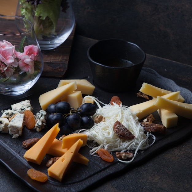 Side view cheese platter with grapes and nuts and honey in tray