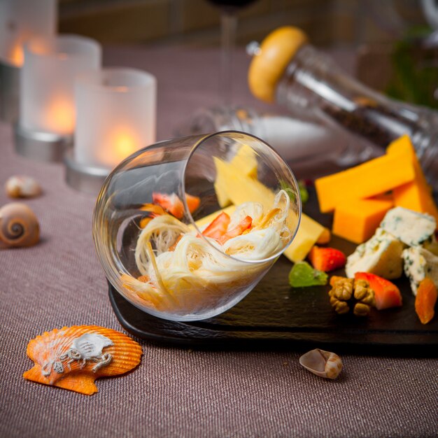 Side view cheese set with glass and candles in wood plate