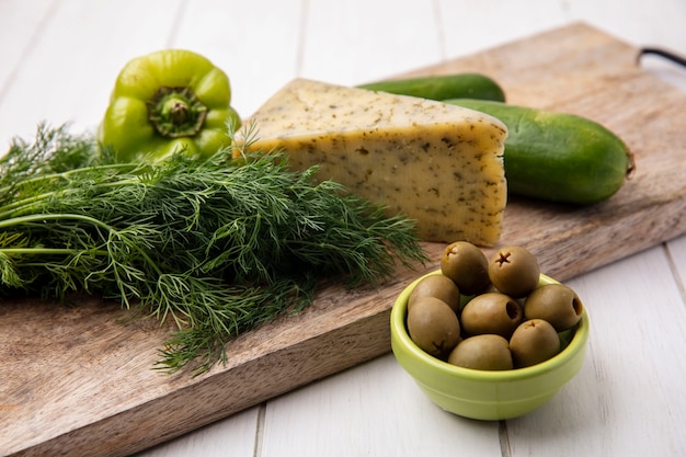 Вид сбоку сыр с огурцами со сладким перцем на подставке с оливками на белой тарелке