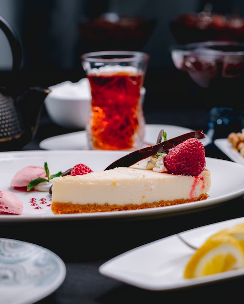 白い皿に新鮮なイチゴで飾られたチーズケーキの側面図