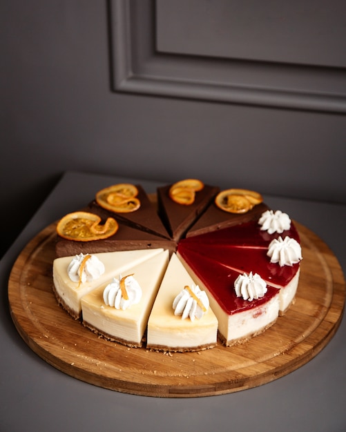 Foto gratuita vista laterale di cheesecake a fette su fette di frutta e vaniglia al cioccolato in lamiera di legno