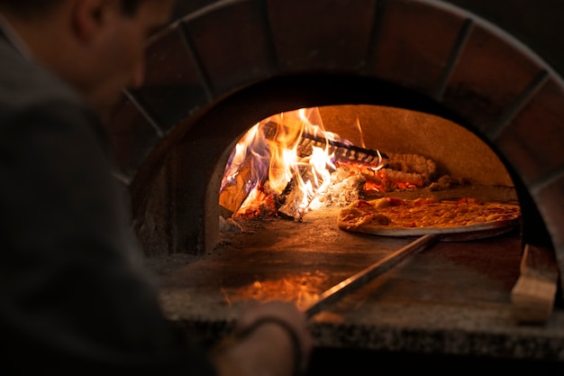 Free photo side view chef baking delicious pizza