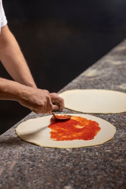 Foto gratuita cuoco unico di vista laterale che prepara pizza