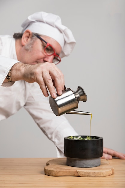 Side view cheg adding oil to guacamole