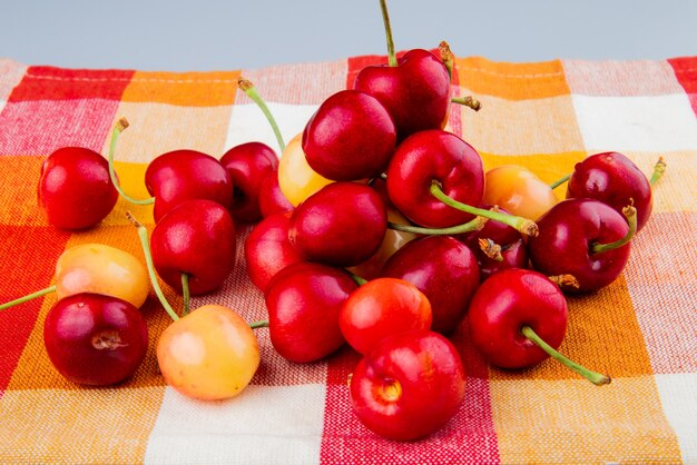 Side view of cherries on plaid cloth and white table