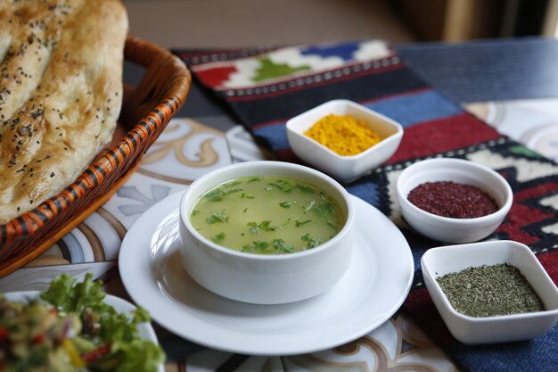 Side view chicken broth with spices and tandoor bread in a basket on the table