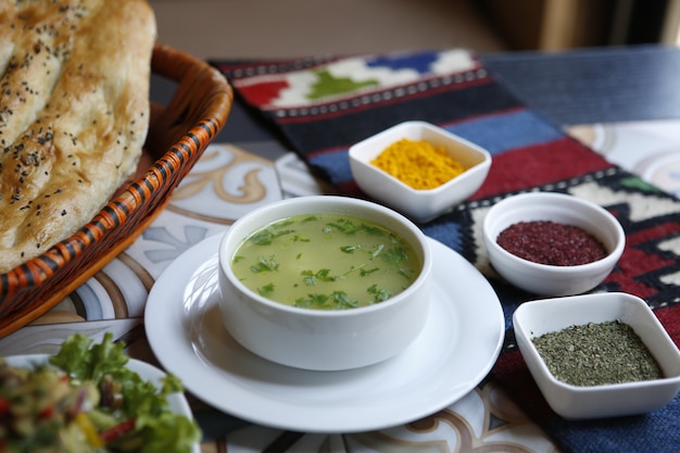 Side view chicken broth with spices and tandoor bread in a basket on the table