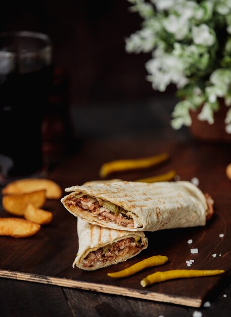 Side view of chicken doner wrapped in lavash on a wooden cutting board