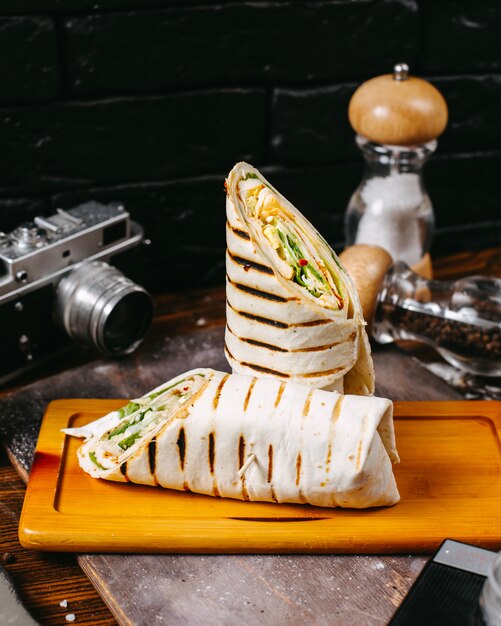 Side view of chicken doner wrapped in lavash on wooden table