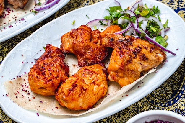 Foto gratuita kebab di pollo di vista laterale con le verdure della cipolla rossa e il crespino secco sulla pita
