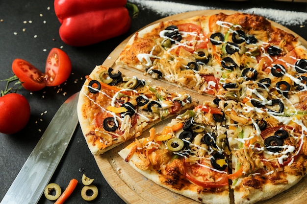 Вид сбоку куриная пицца с помидорами, болгарским перцем и оливками на подносе