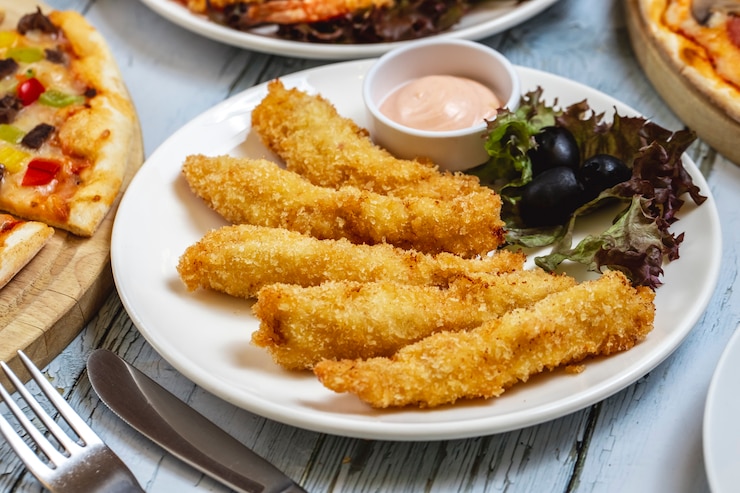 Free Photo side view chicken strips with black olive lettuce and sauce on a plate