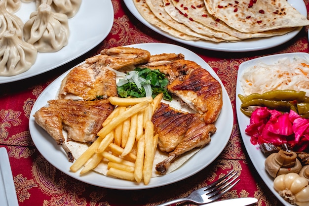 Foto gratuita tabaka del pollo di vista laterale con le patate fritte verdi la cipolla ha marinato la melanzana ed aglio del pepe del cavolo dei funghi dei funghi sul tavolo