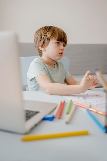 Side view of child at home being tutored with laptop