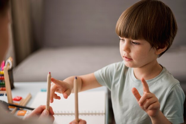 Вид сбоку ребенка учиться считать дома с помощью карандашей