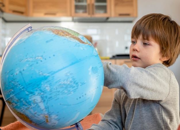 Vista laterale del bambino che guarda il globo terrestre