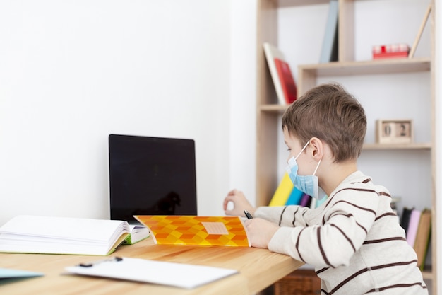 Side view of child with medical mask doing homework