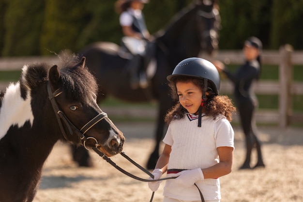 Бесплатное фото Вид сбоку дети учатся кататься на лошадях