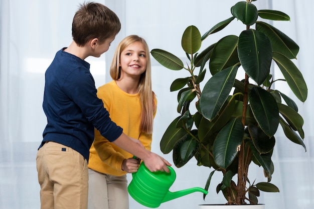 Free photo side view childrens watering flower together