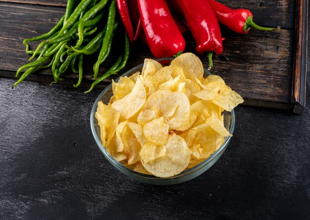 Side view chips in bowl and chilli pepper on cutting board horizontal