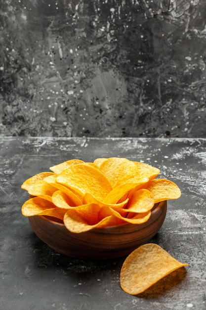 Side view of chips in bowl on dark grey table with dark grey background