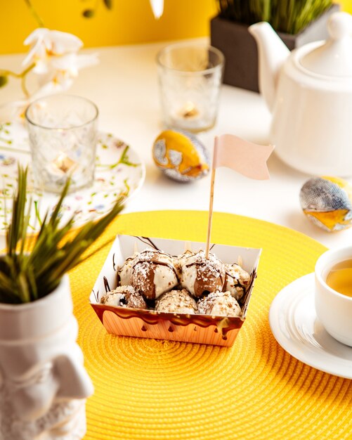 Side view of chocolate balls with coconut sprinkles and strawberry in a cardboard bag