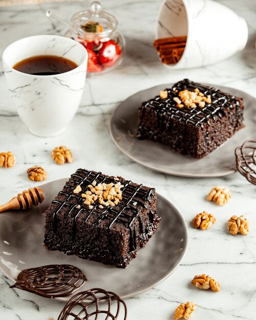 Side view of chocolate brownie cakes on plate served with tea on marble table