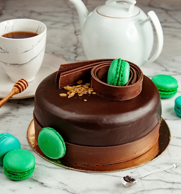녹색 마카롱으로 장식 된 초콜릿 케이크의 측면보기 테이블에 차와 함께 제공