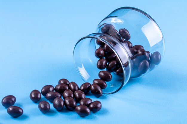 Side view chocolate candies in a glass jar on blue