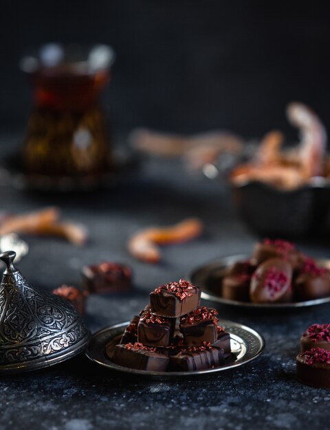 Side view of chocolate candies served with tea on a black wall