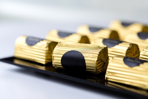 Side view chocolate candy in a gold wrapper on black stand