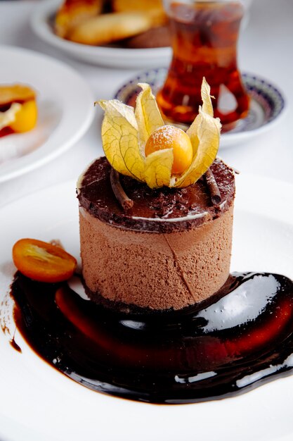 Side view of chocolate cheesecake with kumquat served with tea